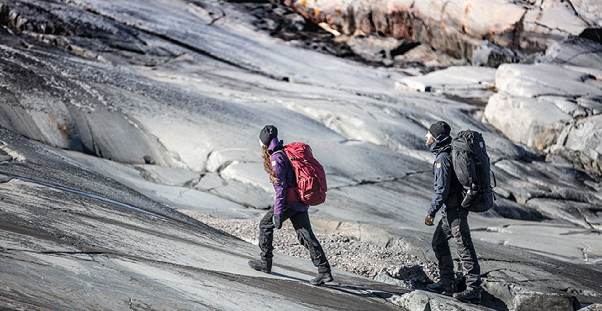 Two people walking up rough rock hiking